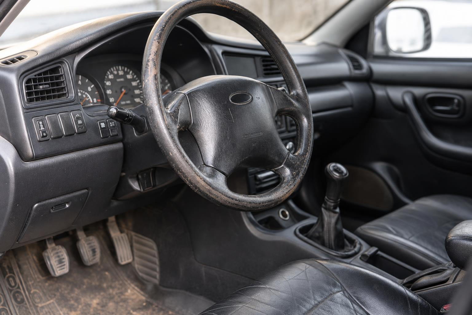 Изношенные педали и потёртый руль в салоне подержанного автомобиля